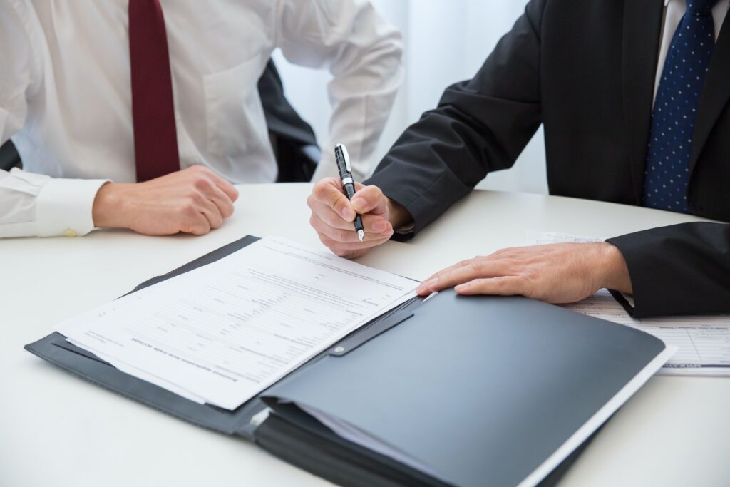 two men in suits signing a paper shareholders agreeement with a fountain pen